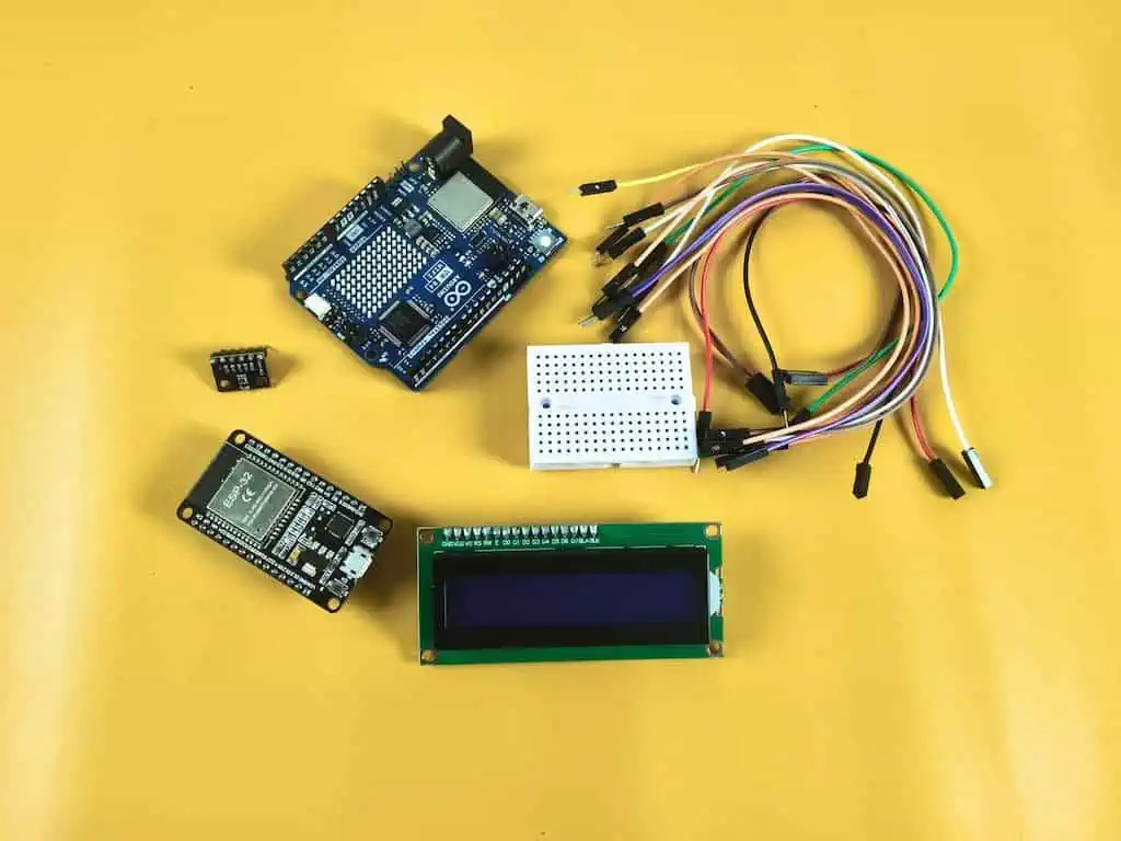 A high-quality comparison of an ESP32 board and an Arduino Uno R4 WiFi on a wooden desk, surrounded by a BMP280 sensor, LCD1602 display, and jumper wires for an IoT weather project.